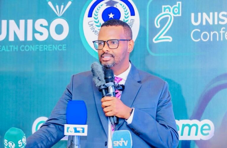 Dr Jalaaludiin holding a microphone and speaking on stage during a professional health conference.