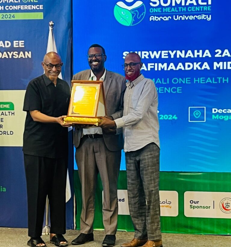 Dr Jalaaludiin standing on stage with fellow professionals while receiving a framed recognition award at a health conference.