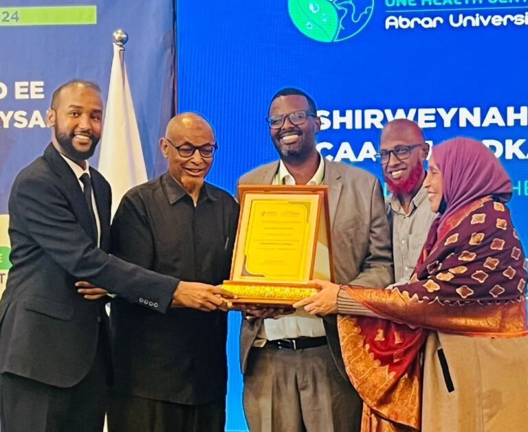 Dr Jalaaludiin and fellow professionals presenting and receiving a framed award at a global health event.
